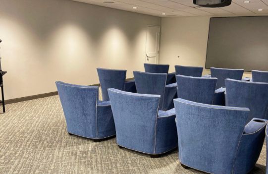 A conference room with rows of blue chairs arranged for a meeting.
