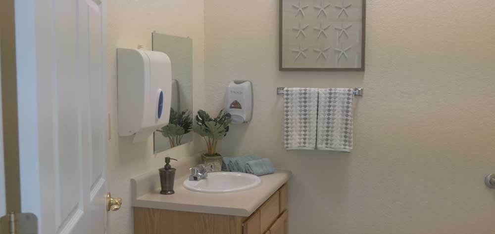 A tidy bathroom corner with a sink, mirror, and neatly hung towels.
