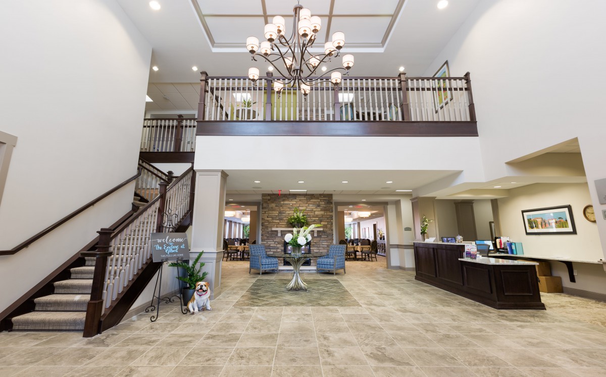 A spacious and elegantly designed lobby with a large chandelier, staircase, and comfortable seating area.