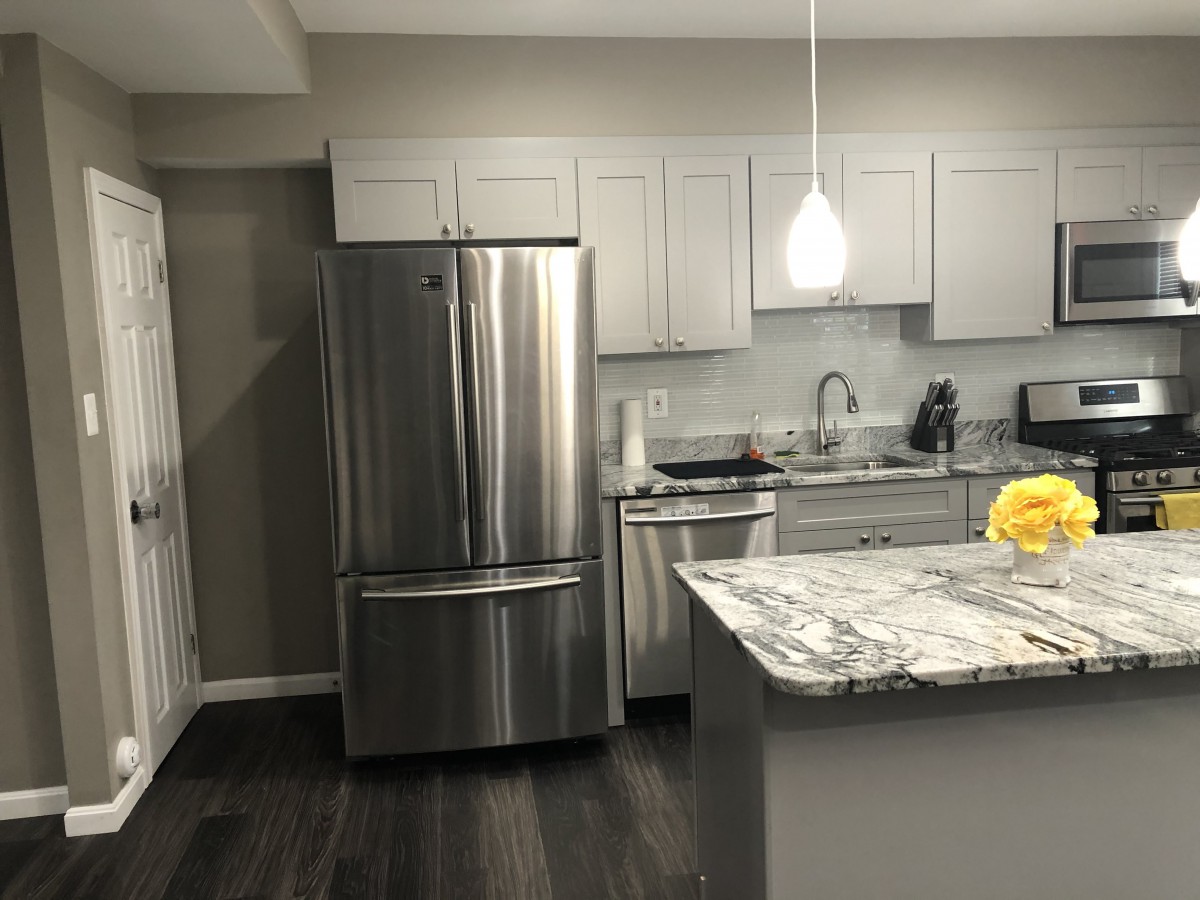 A modern kitchen with stainless steel appliances and marble countertops.