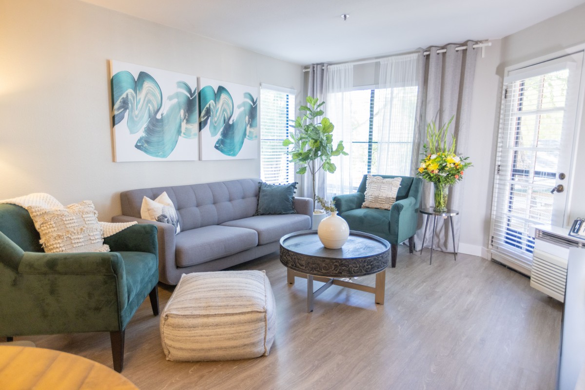 A modern living room with a gray sofa, teal armchairs, and stylish decor.