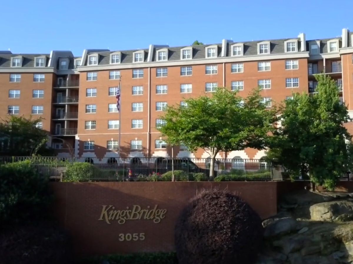 A view of a multi-story brick residential apartment building with trees in front.