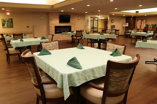 A well-arranged dining area featuring tables with green napkins in a warm and inviting environment.