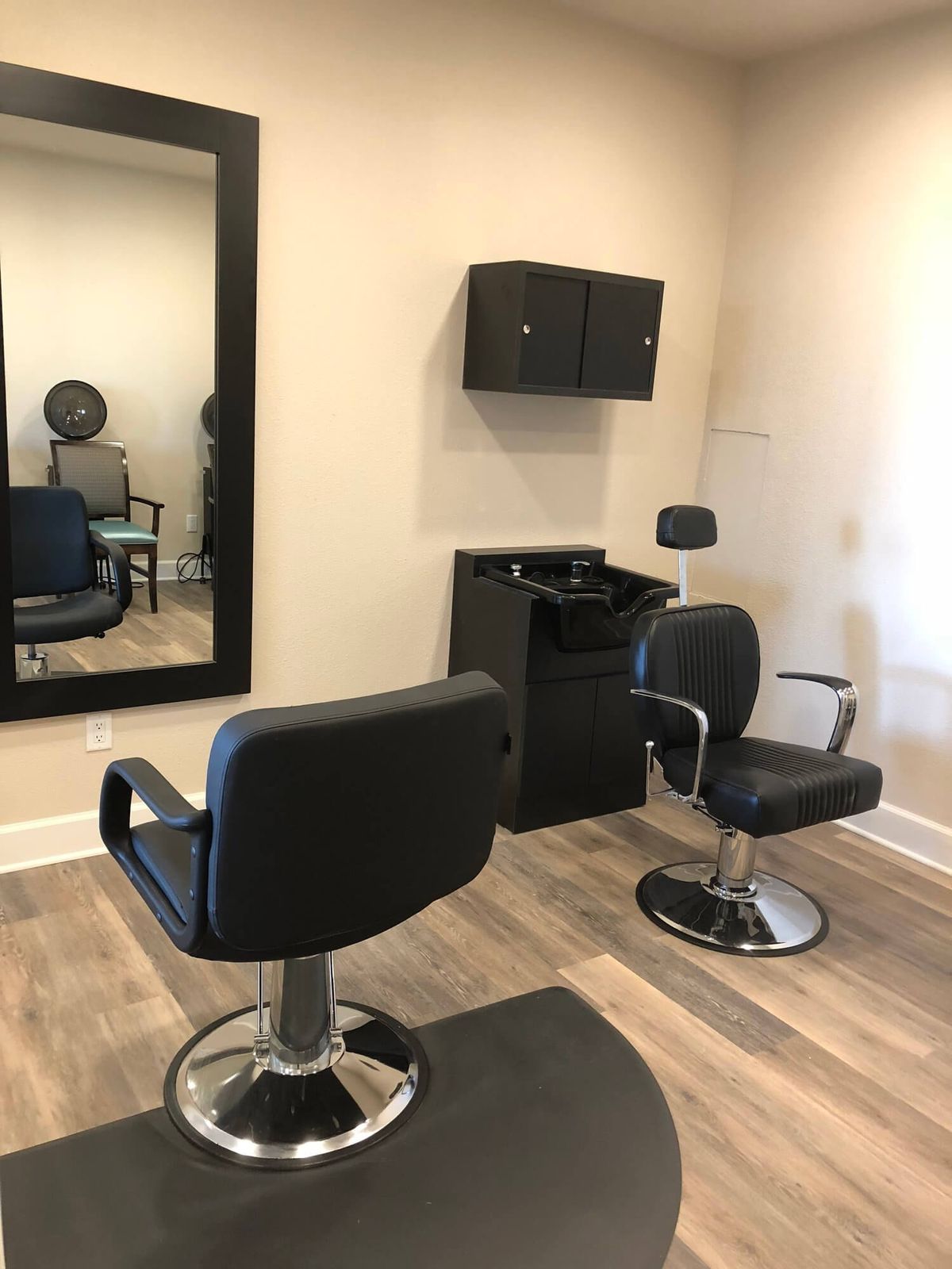 A minimalist salon setup featuring chairs and a large mirror.