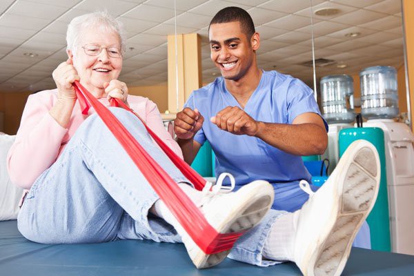 An elderly woman participating in a physical therapy session with a healthcare professional assisting her.