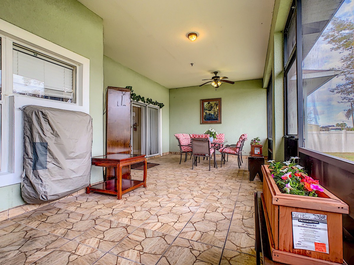 A cozy patio with a dining table set, surrounded by potted plants and decorated with wall art.