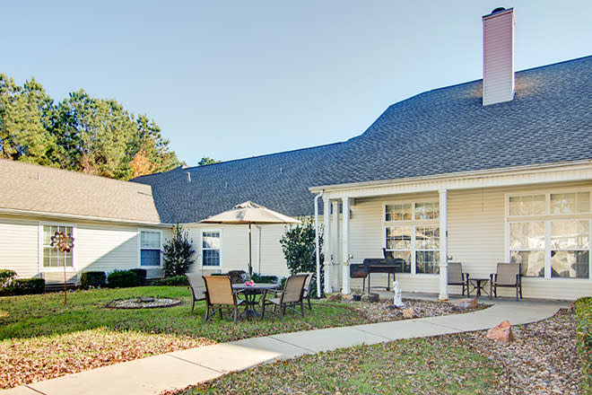 A cozy backyard with a patio and outdoor furniture, surrounded by well-maintained lawns and gardens.