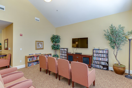 A cozy living room setup featuring comfortable seating, a television, and shelves filled with books or media.