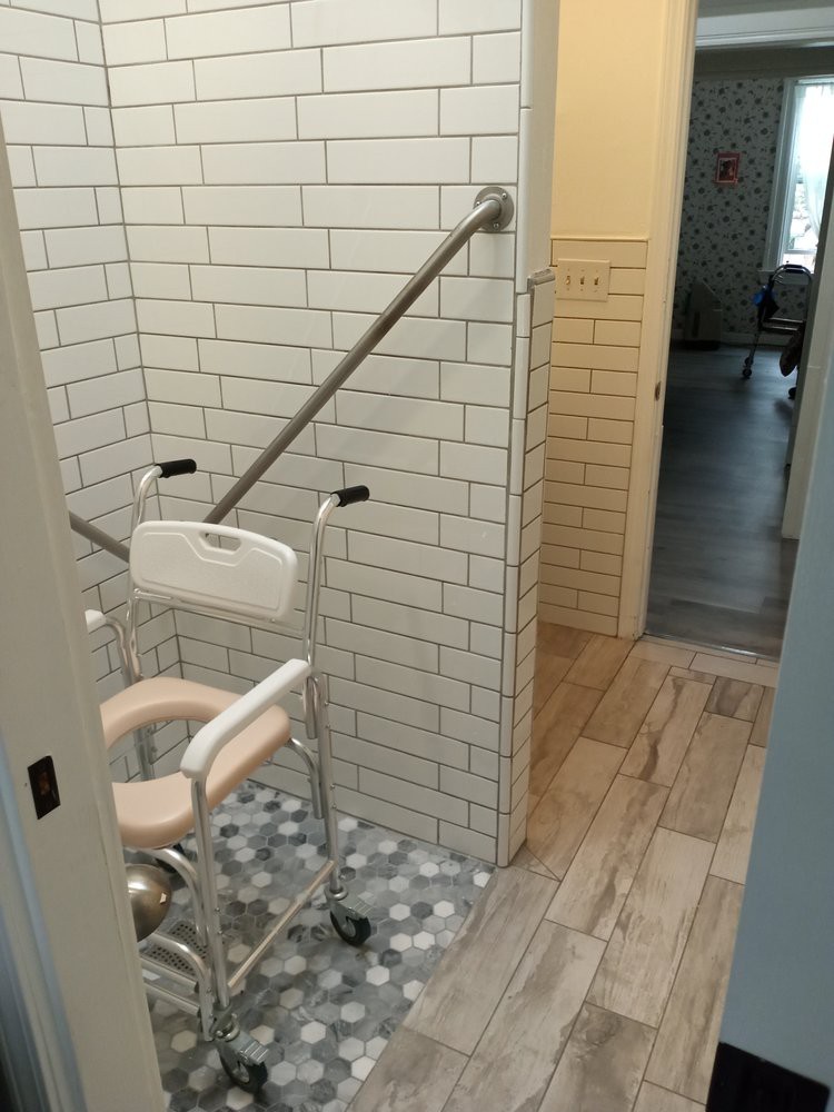 An accessible bathroom with a wheelchair and grab bar installed for ease of use.