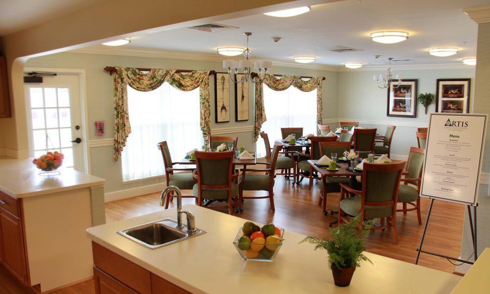 A cozy dining room with elegantly set tables and a view from the kitchen counter.