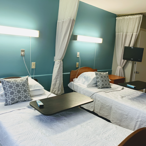 A cozy hotel room featuring twin beds and a calming blue wall.