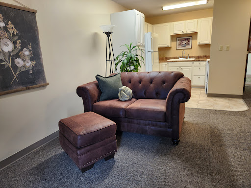 A cozy living room setup featuring a stylish sofa and ottoman, complemented by indoor greenery.