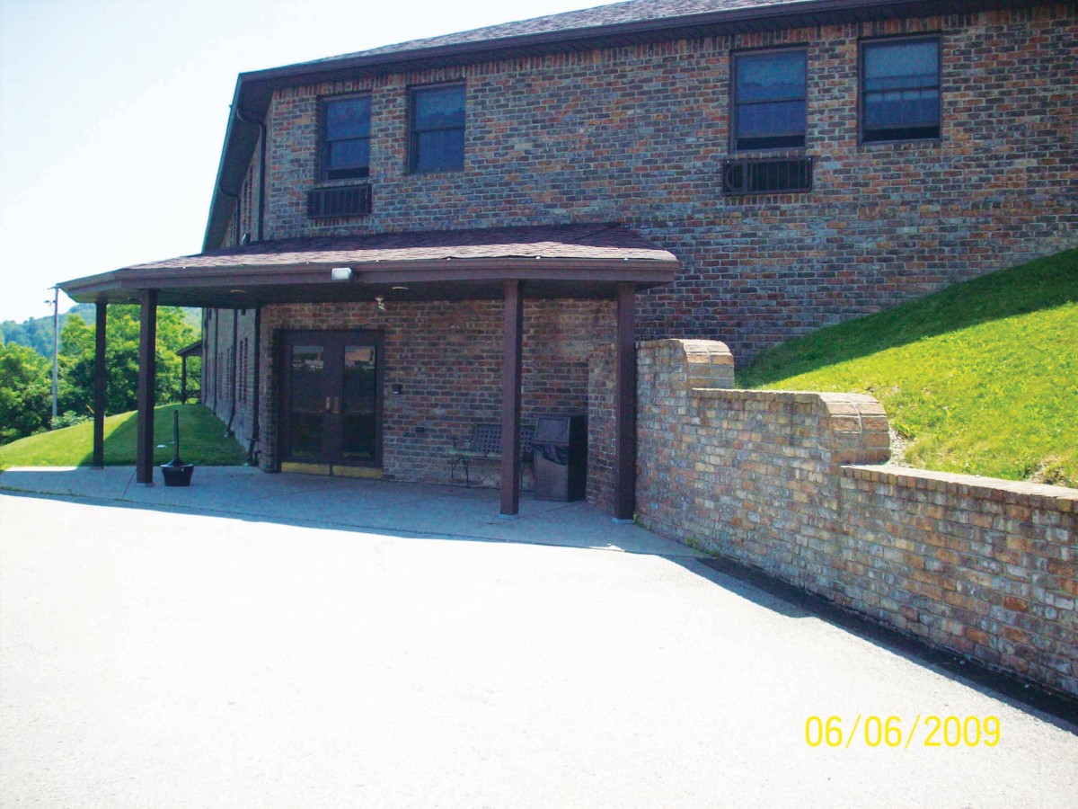 A brick building entrance with an awning and a concrete wall.