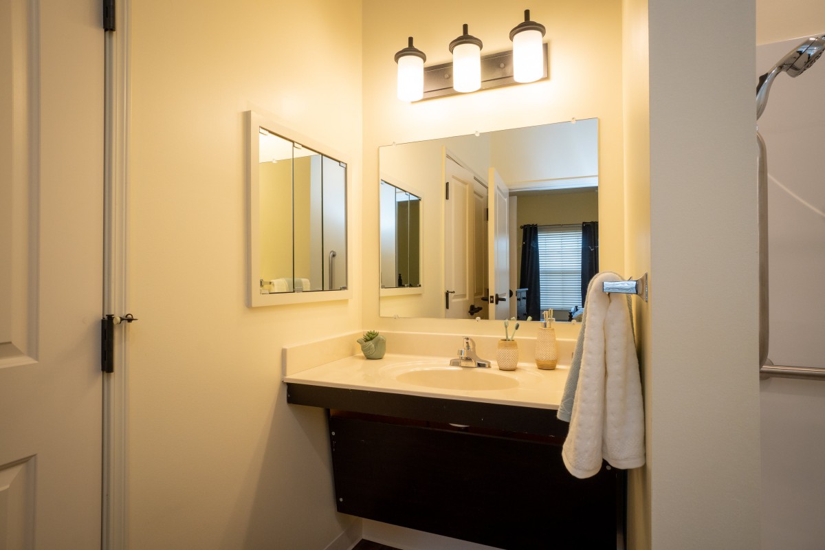 A well-lit modern bathroom with a mirror and sink area, featuring a neatly hung towel.