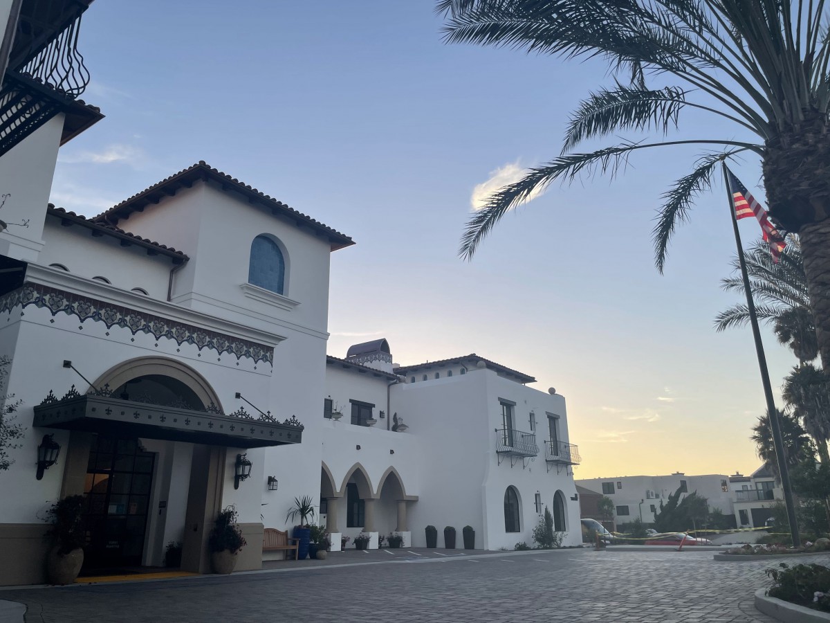 A Mediterranean-style building at sunset with palm trees and a clear sky.