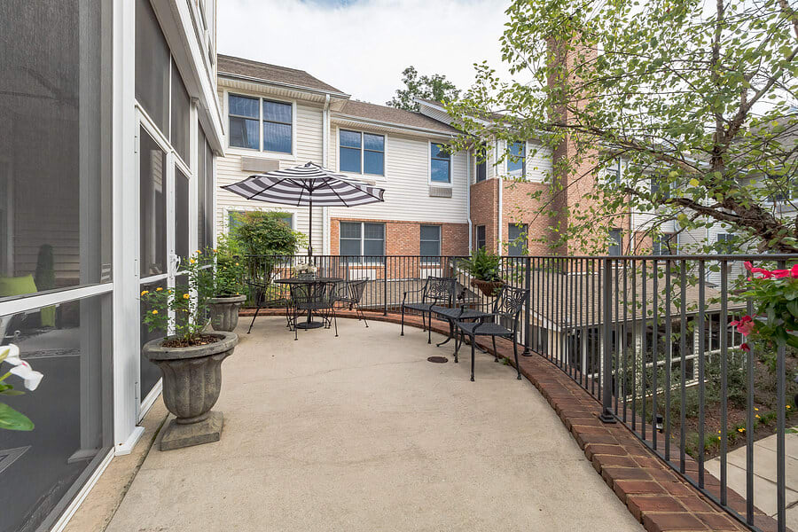 A cozy patio with tables and chairs, featuring large umbrellas and surrounded by a building exterior.
