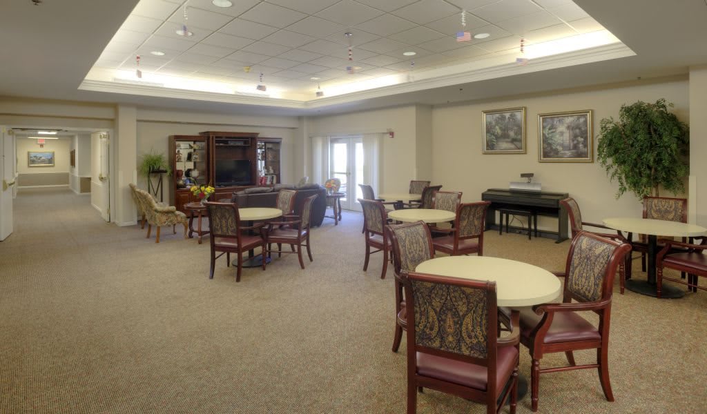 A cozy dining area with tables and chairs, featuring a piano in the corner.