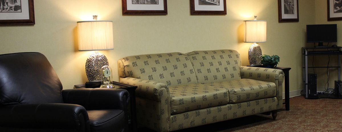 A comfortable living room setup featuring a patterned sofa, a side lamp, and framed wall art.