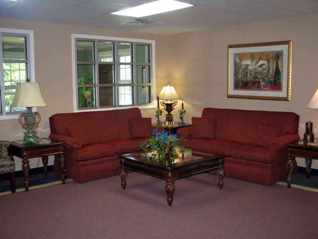 A cozy living room with red sofas and a central coffee table under soft lighting.