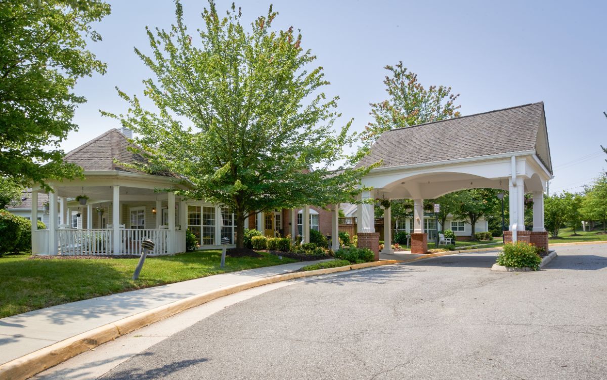 A well-maintained building entrance with a covered driveway and lush green landscaping.