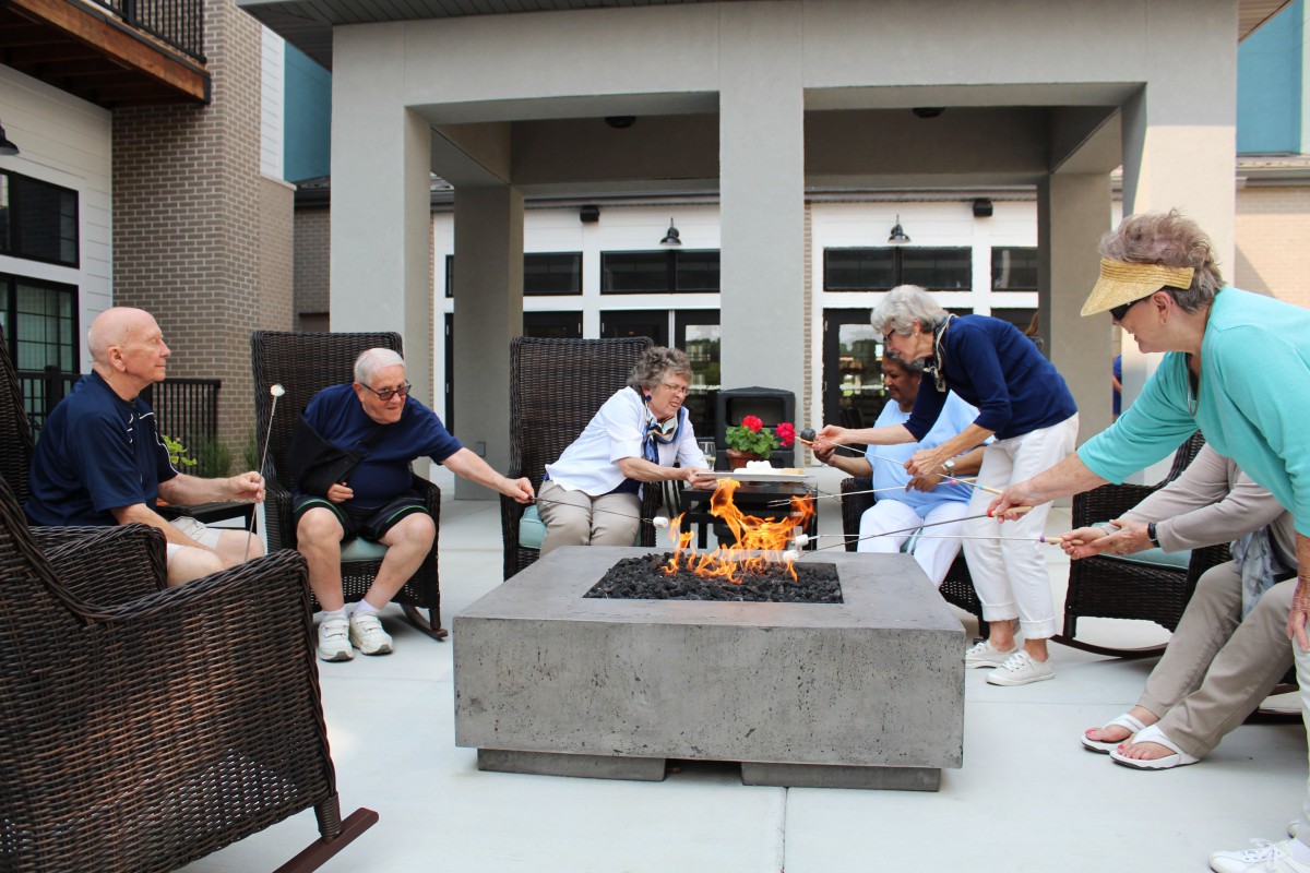 A group of seniors enjoying a relaxing time around a fire pit on a patio.