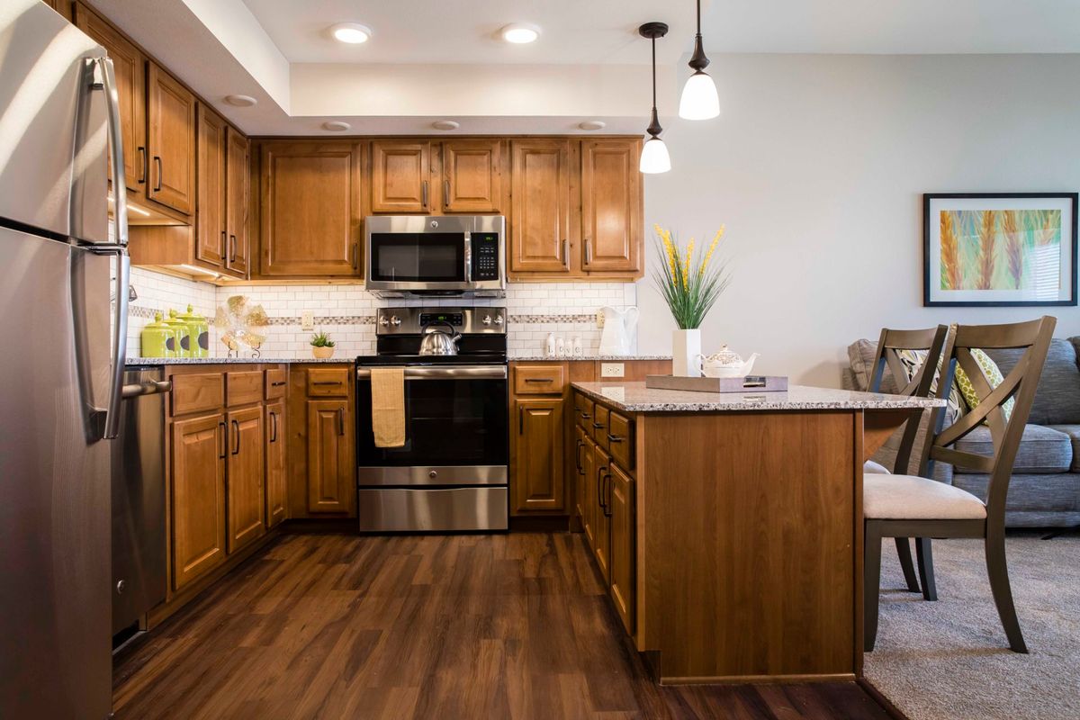 A modern kitchen with wooden cabinets, stainless steel appliances, and a central island.