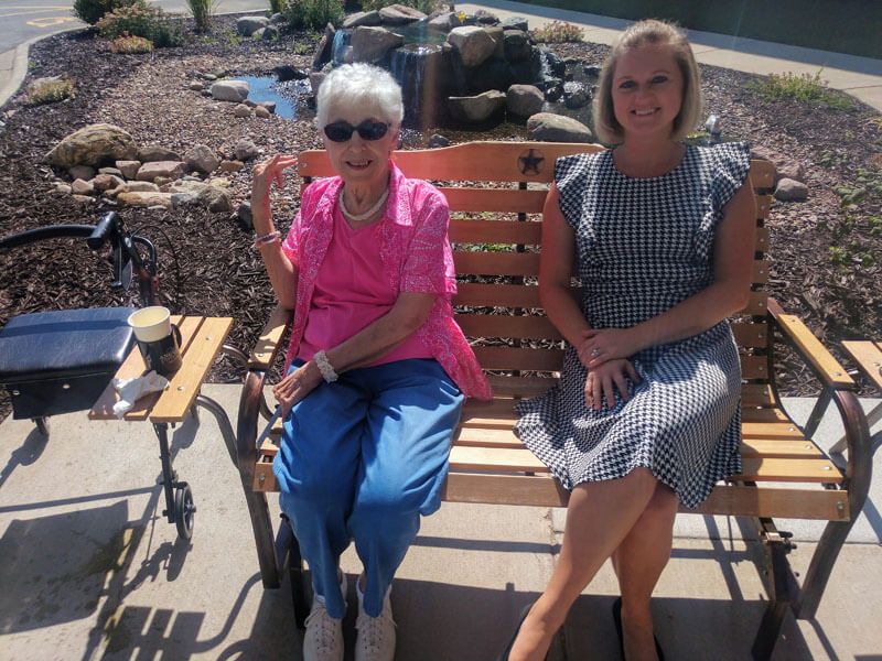 Two women sitting on a bench enjoying a sunny day.