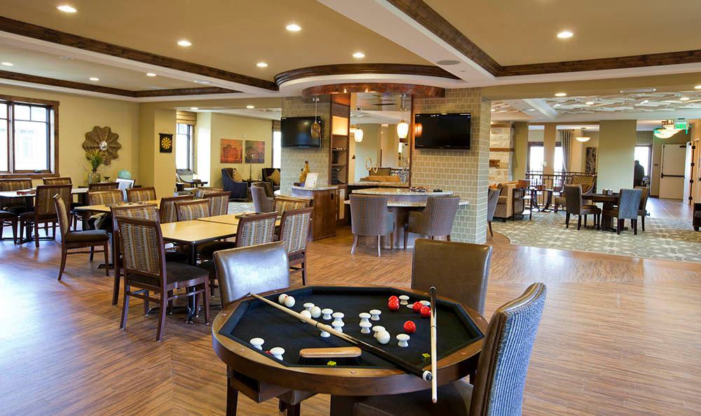 A modern recreational room featuring a pool table and various seating areas.