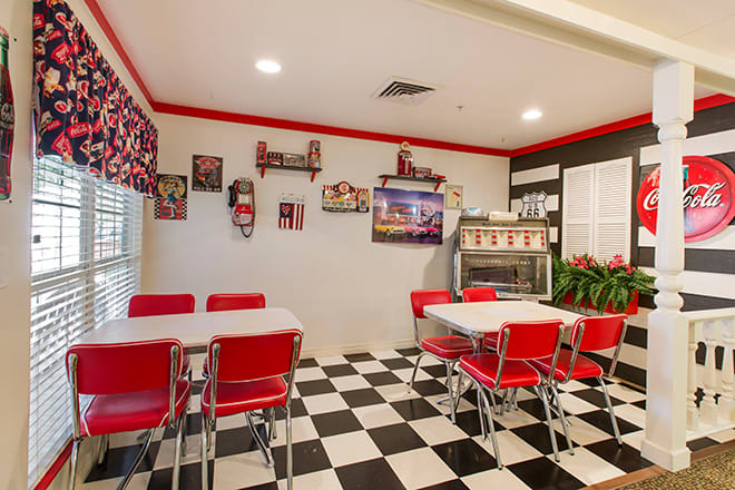 A retro-style diner with a black and white checkered floor, red chairs, and vintage decor.