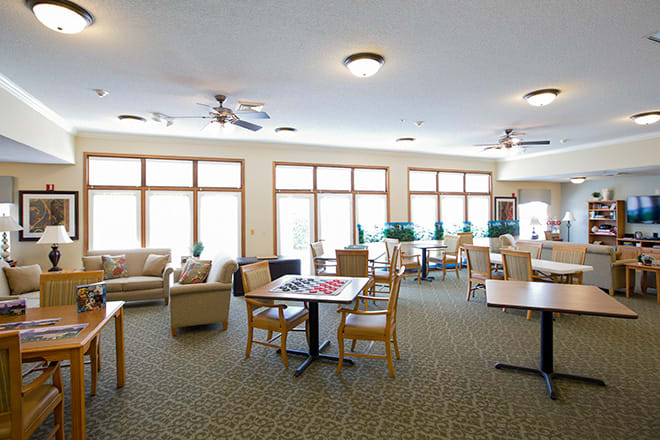 A spacious lounge with tables, chairs, and large windows.