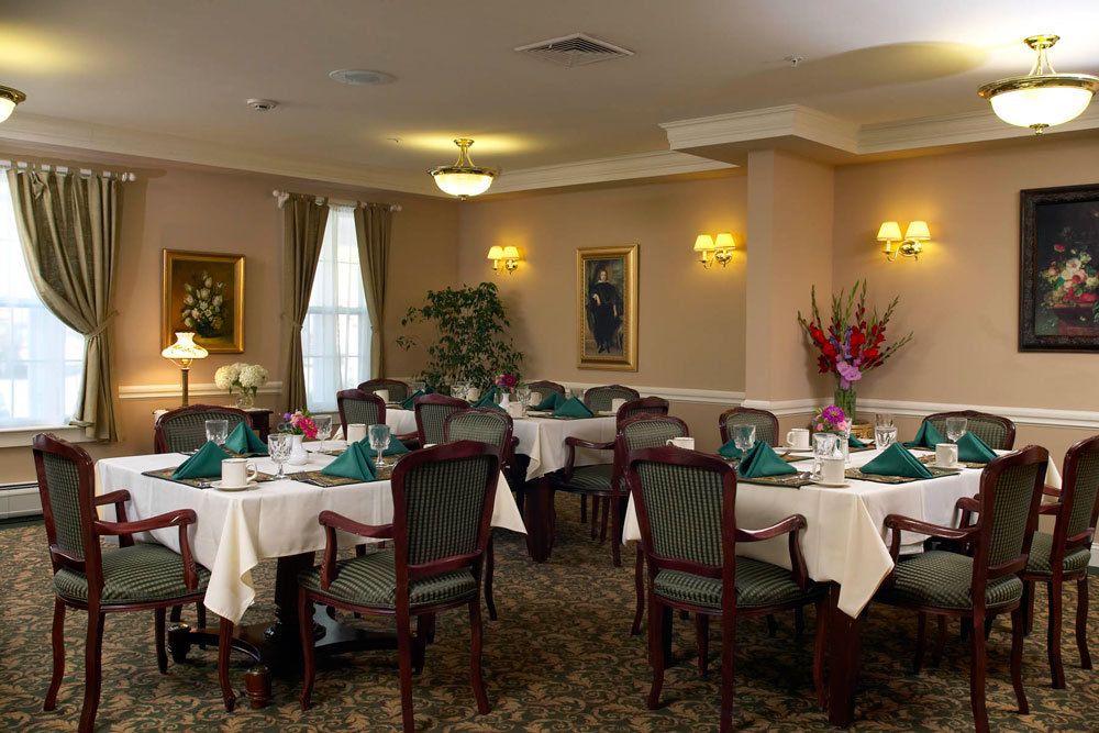 An elegant dining room with neatly arranged tables and chairs, set for a formal meal.