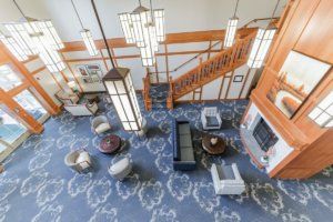 A spacious lobby with elegant chandeliers, a patterned blue carpet, and comfortable seating areas.