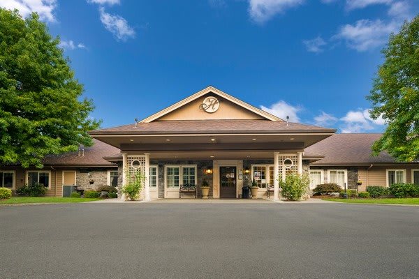A welcoming building facade with a central clock and landscaped entrance under a clear blue sky.