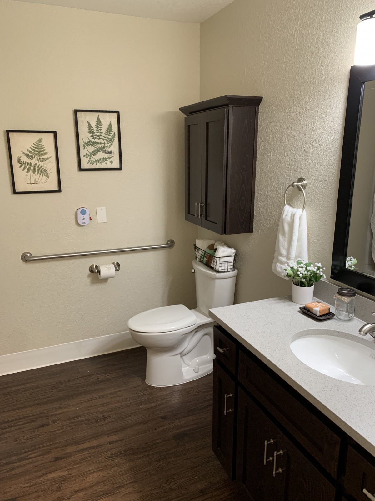 A well-organized bathroom featuring a toilet, sink with a counter, mirror, and decorative elements.