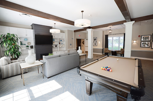 A stylish and spacious living room featuring a pool table, modern furnishings, and ample natural light.