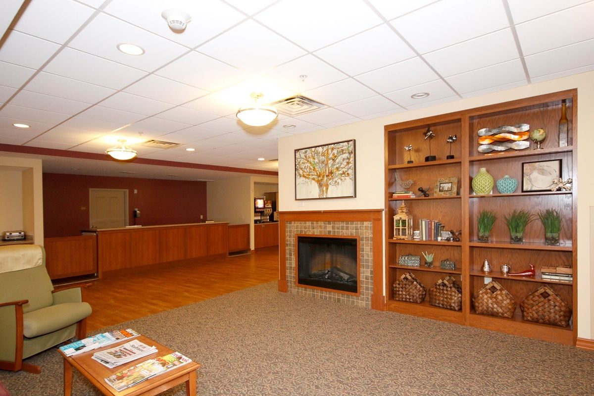 A cozy reception area with a fireplace and bookshelf, featuring comfortable seating for guests.