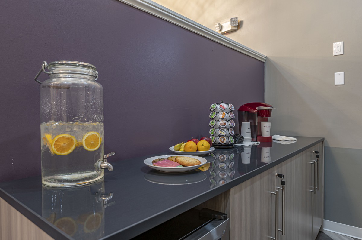 A well-organized kitchen counter with a water dispenser, fruit plate, and coffee maker.