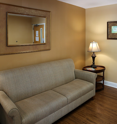 A cozy living room featuring a beige sofa, a decorative mirror, and a warm lamp.