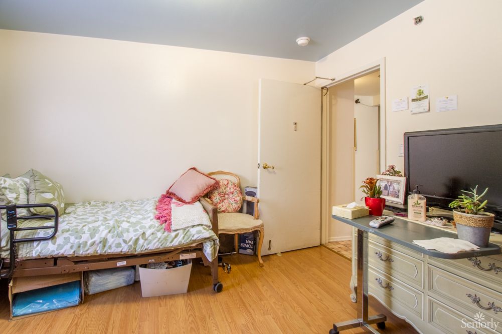 A cozy bedroom with a single bed, pillows, a chair, and a small desk.