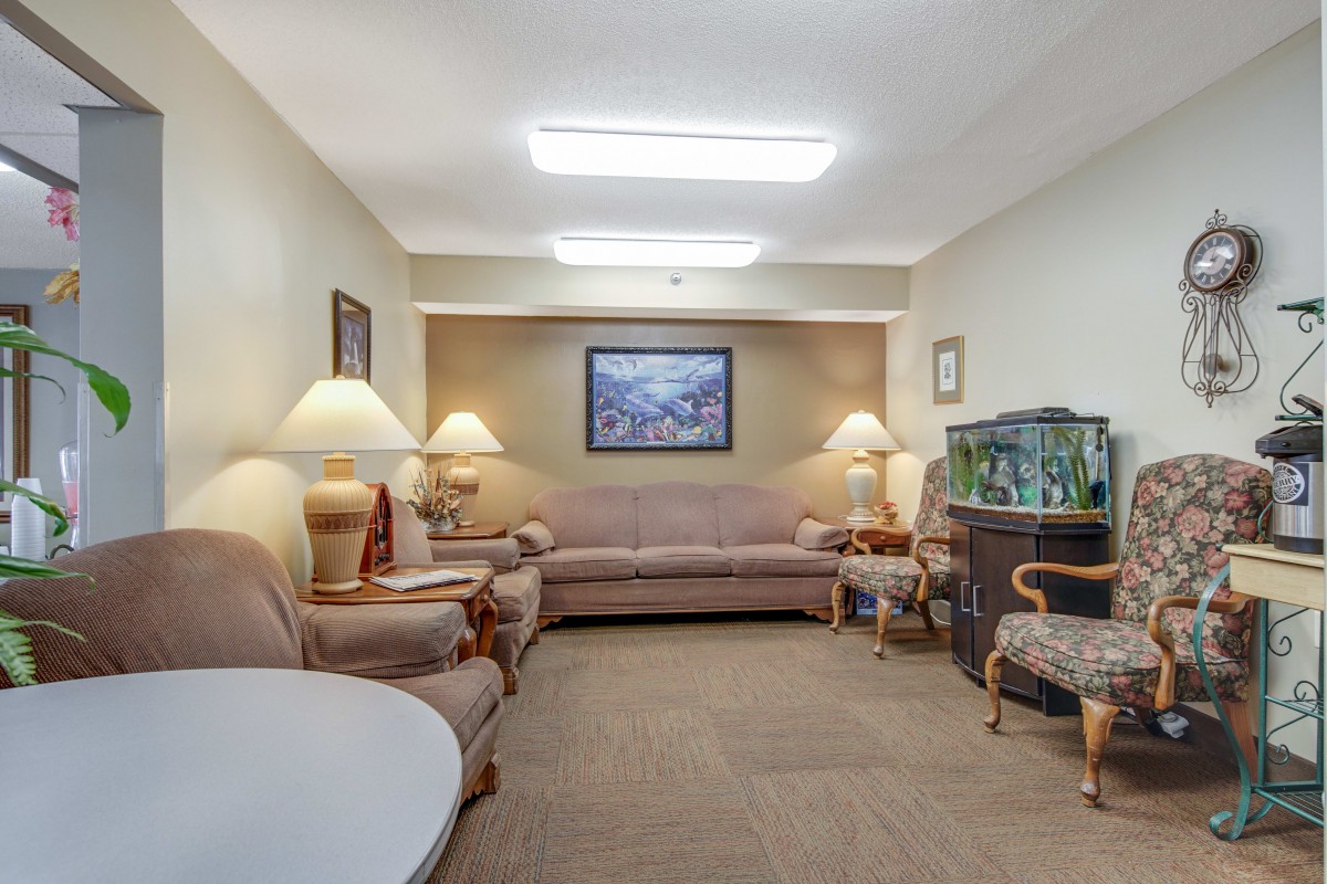 A cozy living room with a sofa, armchairs, and a fish tank.