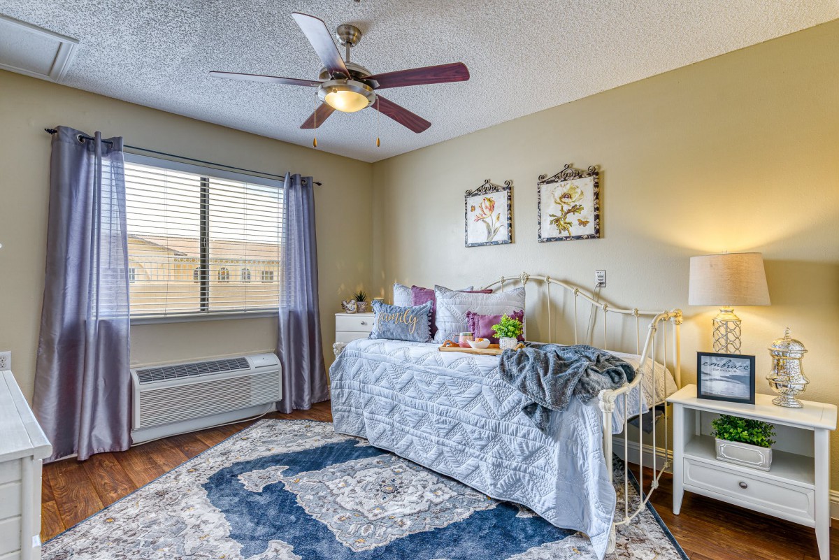 A cozy bedroom with a single bed, ceiling fan, and decorative elements.