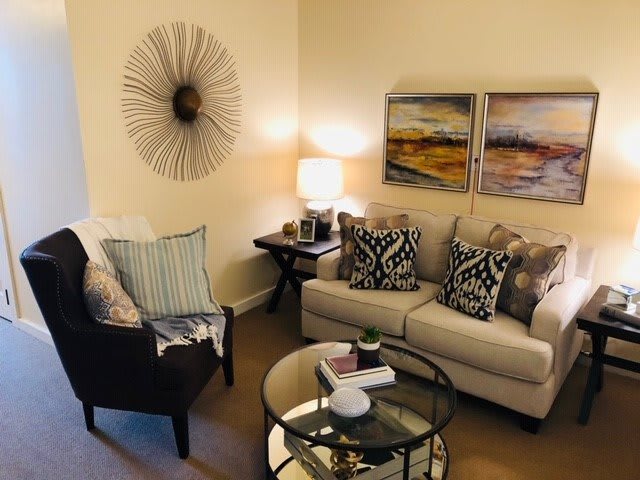 A cozy living room with modern decor, featuring a sofa, armchair, and contemporary wall art.