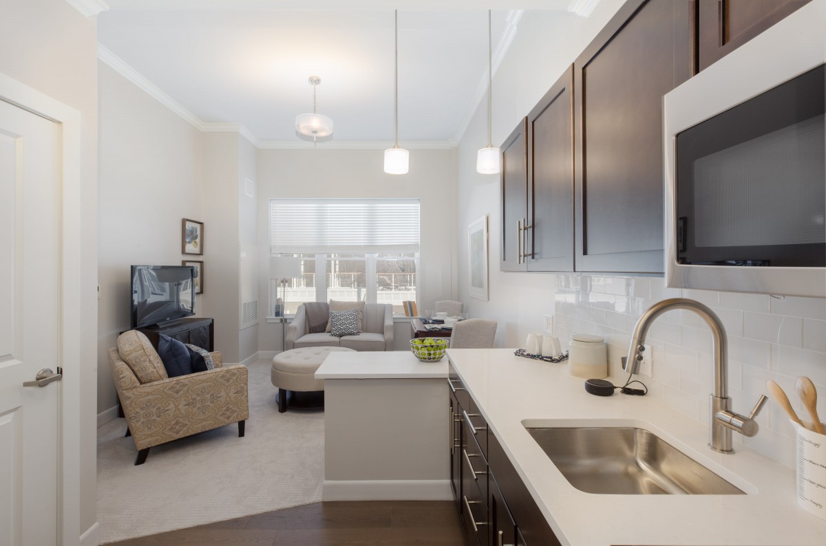 A modern open-plan apartment interior featuring a stylish kitchen and cozy living room.