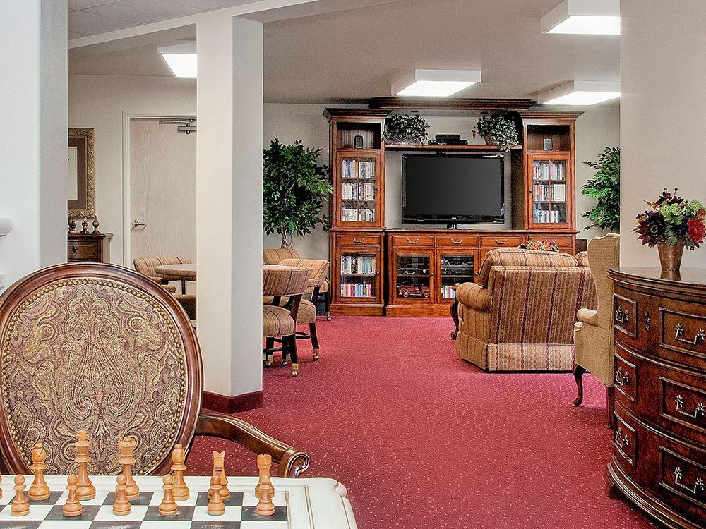 A cozy living room with a chessboard, bookshelves, and a TV.