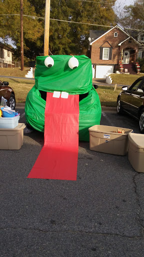 A whimsical green inflatable character with a long red tongue, perfect for entertaining at events.