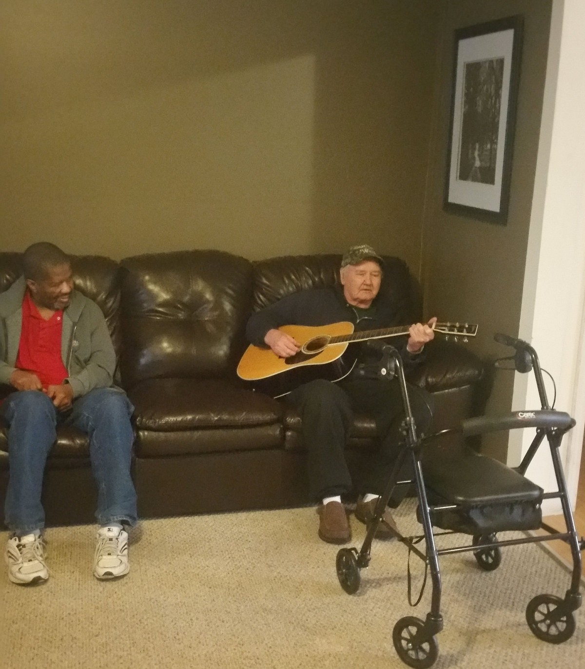 Two people sitting on a couch, one playing a guitar.