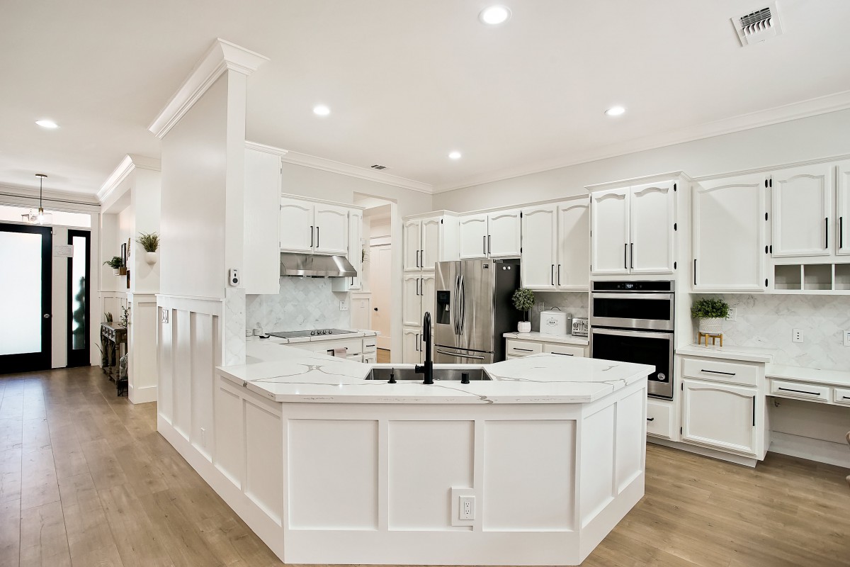 A modern kitchen with white cabinetry and stainless steel appliances.