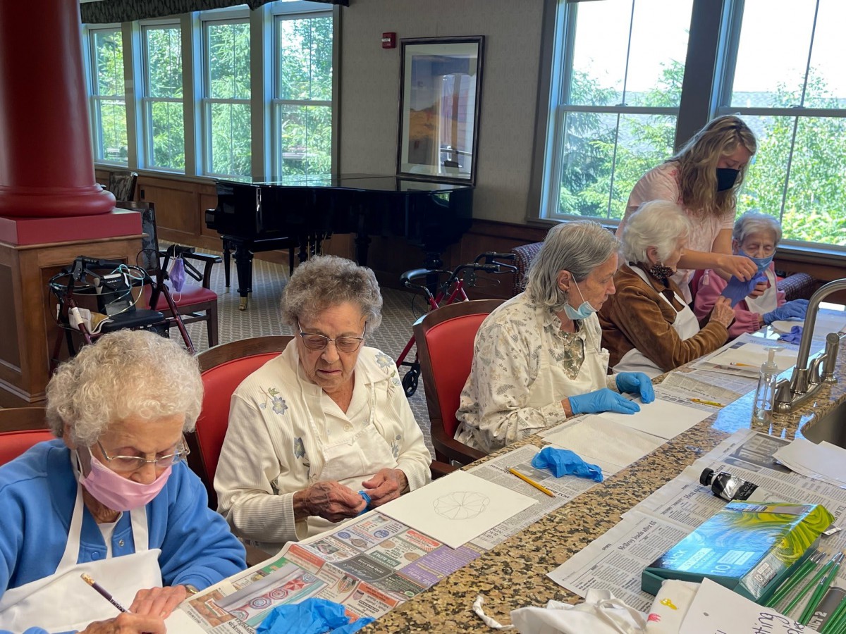 A group of elderly individuals participating in an arts and crafts activity at a table indoors.
