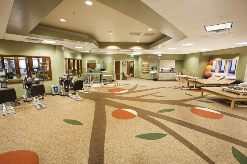 A spacious rehabilitation center featuring various exercise equipment and therapy areas.