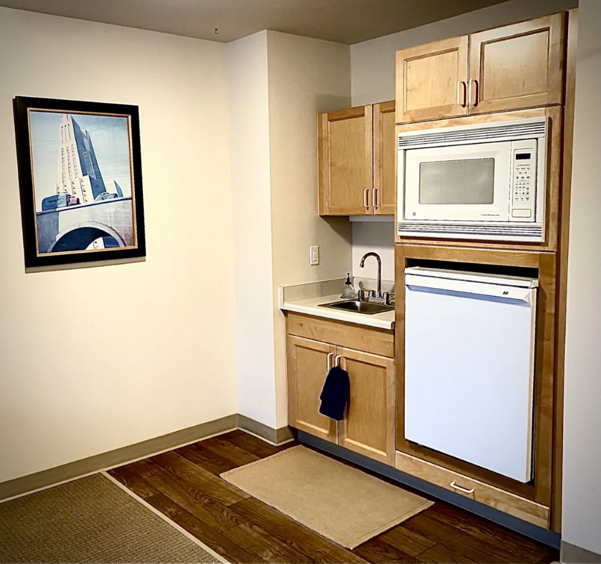 A compact kitchen area with a microwave, sink, and cabinets in an apartment setting.